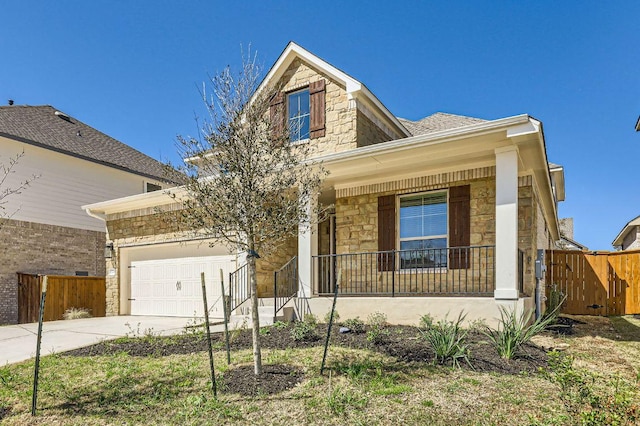 traditional-style home featuring stone siding, covered porch, concrete driveway, and fence