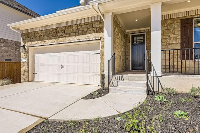 view of exterior entry with a garage, stone siding, a porch, and driveway