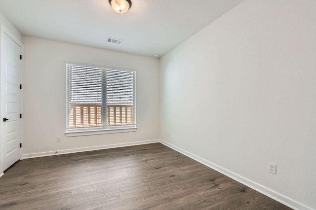 unfurnished room featuring baseboards, visible vents, and dark wood-style flooring