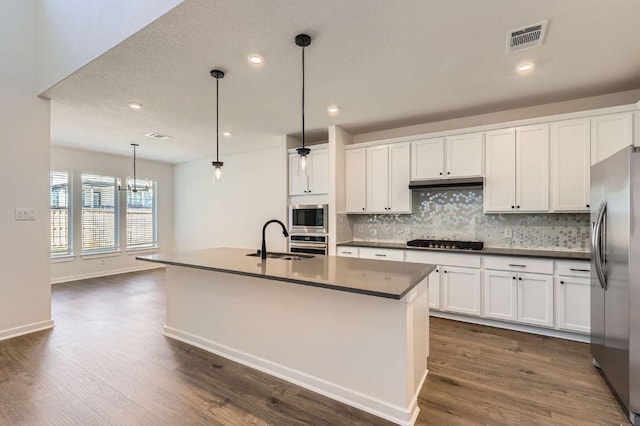 kitchen featuring tasteful backsplash, visible vents, under cabinet range hood, stainless steel appliances, and a sink