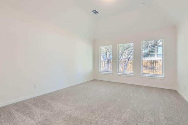 spare room with visible vents, light carpet, baseboards, and vaulted ceiling