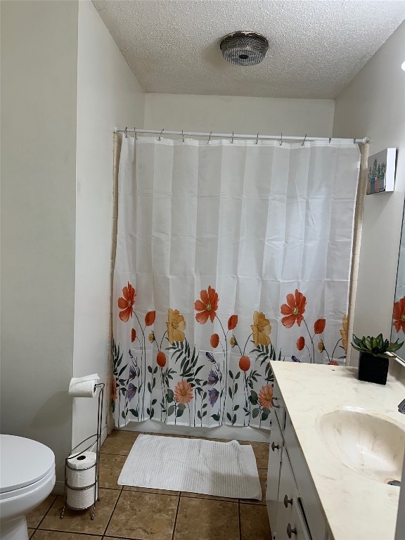 bathroom with tile patterned flooring, a textured ceiling, vanity, and toilet