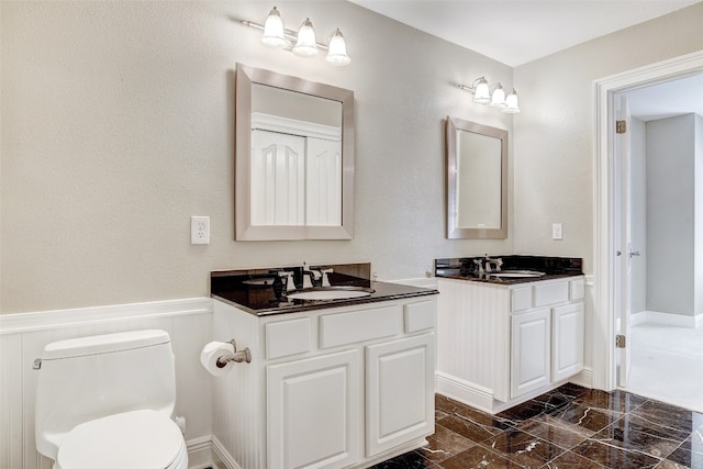 bathroom featuring tile patterned flooring, toilet, and dual vanity