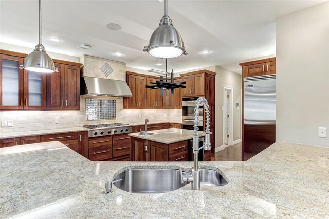 kitchen with stainless steel appliances, pendant lighting, decorative backsplash, and light stone countertops