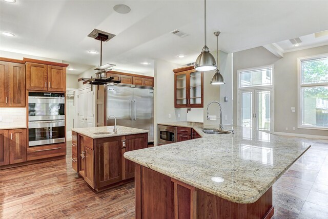 kitchen featuring decorative backsplash, hardwood / wood-style floors, sink, a center island, and built in appliances