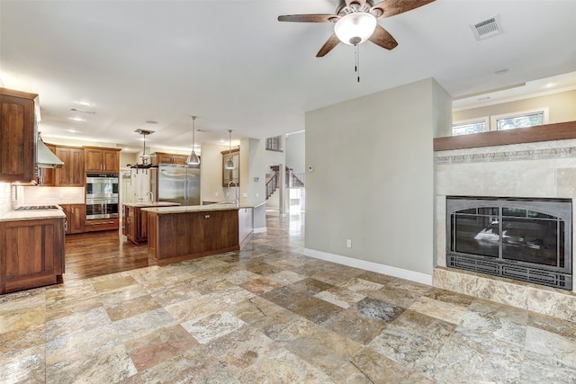 kitchen featuring appliances with stainless steel finishes, tile patterned floors, a high end fireplace, and a kitchen island