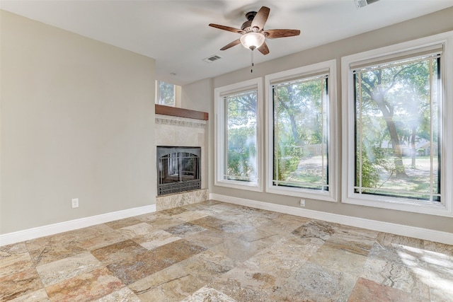 unfurnished living room featuring ceiling fan, a fireplace, and light tile patterned flooring