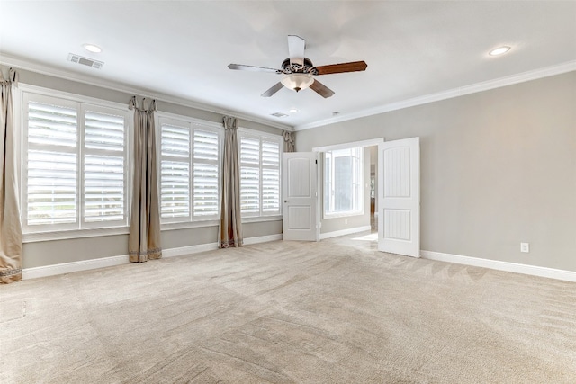 spare room with ceiling fan, crown molding, and light colored carpet