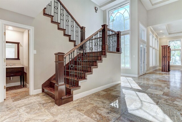 stairs featuring sink, a raised ceiling, a towering ceiling, and tile patterned floors