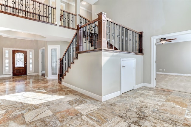 tiled foyer with ceiling fan and a high ceiling