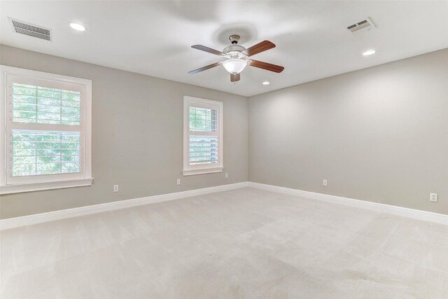 carpeted empty room with a wealth of natural light and ceiling fan