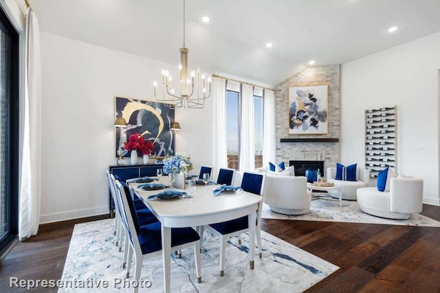 dining room featuring an inviting chandelier, lofted ceiling, a fireplace, and dark hardwood / wood-style flooring