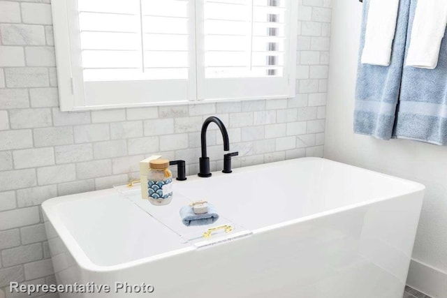 bathroom featuring plenty of natural light, a tub, and sink