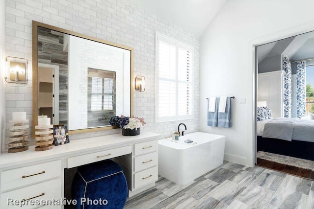 bathroom with a bath, tile walls, lofted ceiling, and vanity