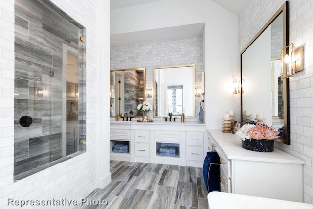 bathroom with brick wall, vanity, hardwood / wood-style floors, and an enclosed shower