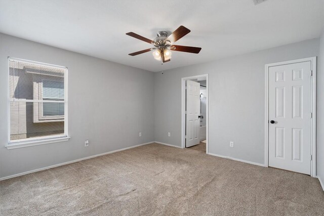 unfurnished bedroom with light colored carpet, connected bathroom, and ceiling fan