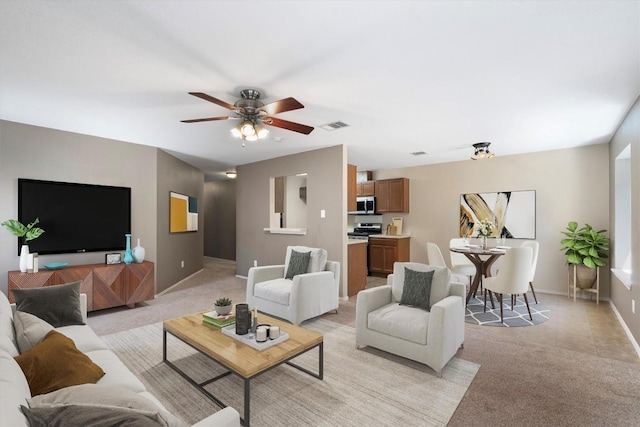 living room featuring baseboards, a ceiling fan, visible vents, and light colored carpet