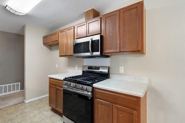 kitchen featuring light colored carpet and appliances with stainless steel finishes