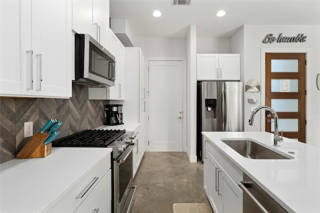 kitchen with backsplash, concrete floors, white cabinetry, sink, and stainless steel appliances