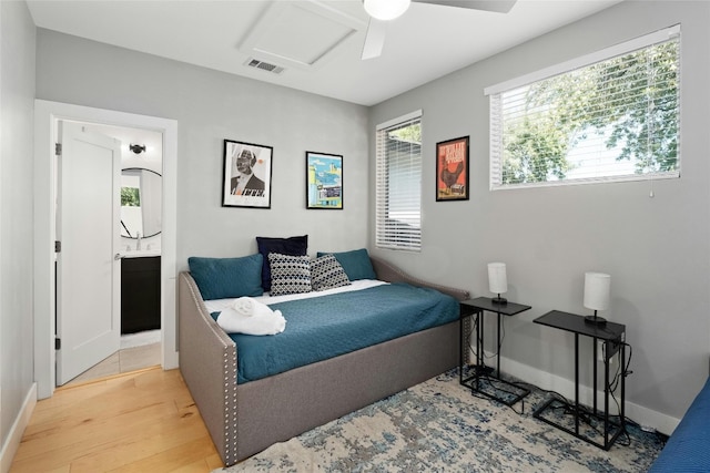 bedroom with ceiling fan, light wood-type flooring, and ensuite bath