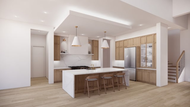 kitchen with light hardwood / wood-style flooring, decorative backsplash, stainless steel refrigerator, sink, and a center island