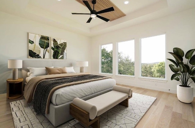 bedroom with ceiling fan, a raised ceiling, and light hardwood / wood-style floors