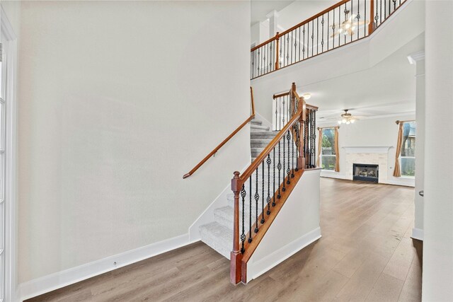 staircase with a high ceiling, wood-type flooring, and ceiling fan