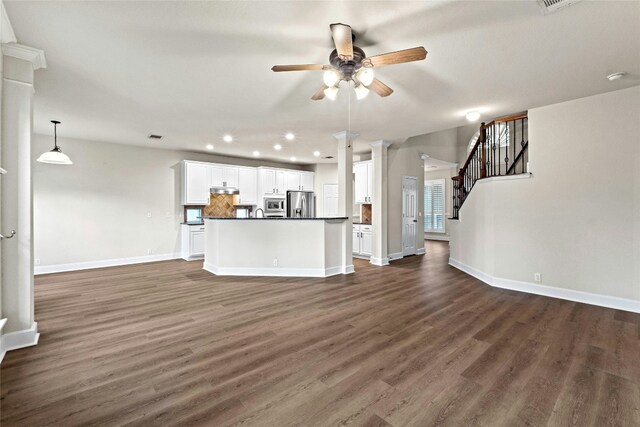 unfurnished living room featuring ceiling fan, dark hardwood / wood-style floors, and decorative columns