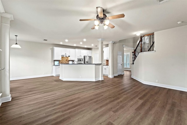 unfurnished living room featuring dark wood finished floors, stairway, baseboards, and ceiling fan