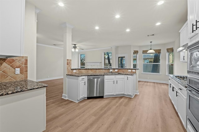 kitchen featuring white cabinetry, pendant lighting, stainless steel appliances, and dark stone counters