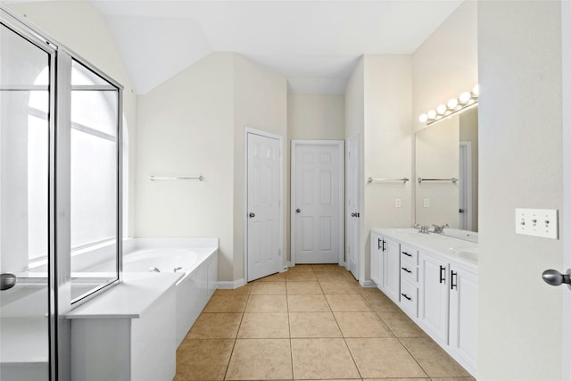 bathroom with a washtub, vanity, tile patterned flooring, and lofted ceiling