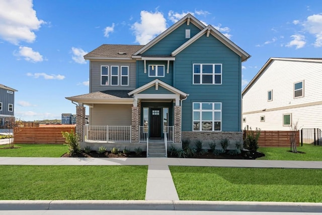 craftsman-style home featuring brick siding, covered porch, a front yard, and fence