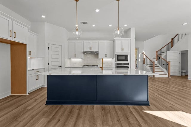 kitchen featuring pendant lighting, white cabinetry, oven, and built in microwave