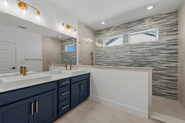 bathroom featuring tiled shower, vanity, and tile patterned flooring