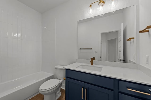 full bathroom with hardwood / wood-style flooring, vanity, tub / shower combination, and toilet