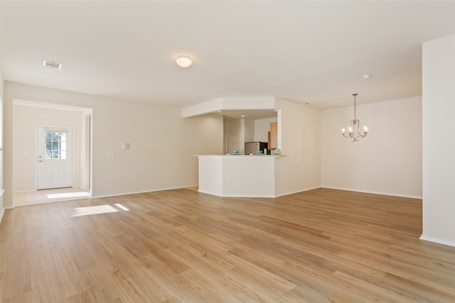 unfurnished living room with light hardwood / wood-style floors and a chandelier