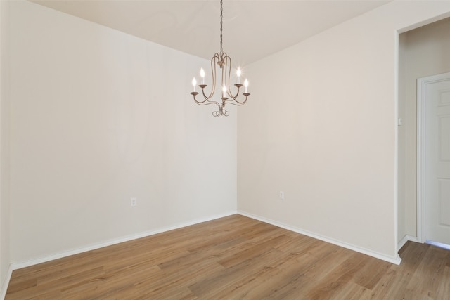 unfurnished room with hardwood / wood-style flooring and a chandelier