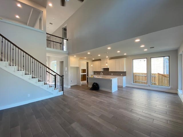 unfurnished living room featuring high vaulted ceiling, dark wood-type flooring, and sink