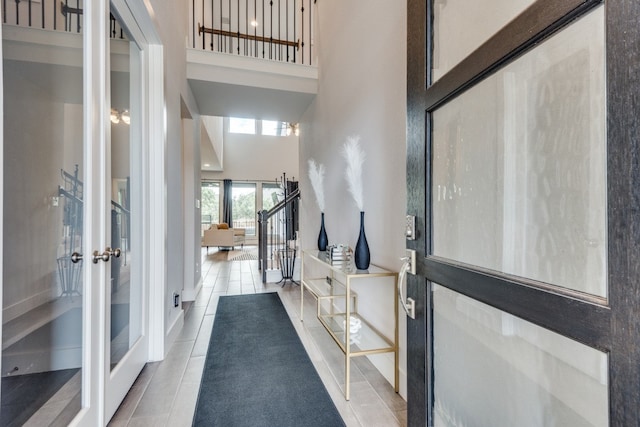 entryway featuring tile patterned floors, a towering ceiling, and french doors