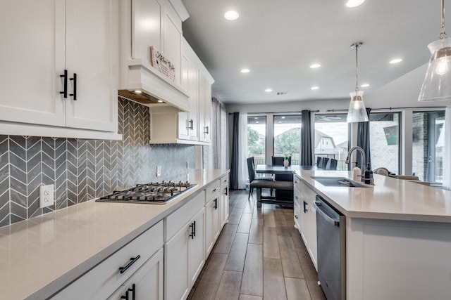 kitchen with a kitchen island with sink, hardwood / wood-style floors, decorative light fixtures, sink, and appliances with stainless steel finishes