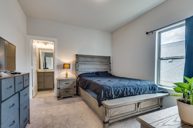 bedroom featuring ensuite bathroom and light colored carpet