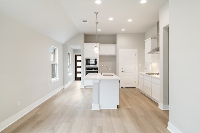 kitchen featuring light hardwood / wood-style flooring, a kitchen island with sink, white cabinetry, sink, and decorative light fixtures