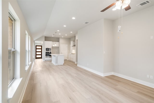 unfurnished living room featuring sink, light hardwood / wood-style flooring, and ceiling fan