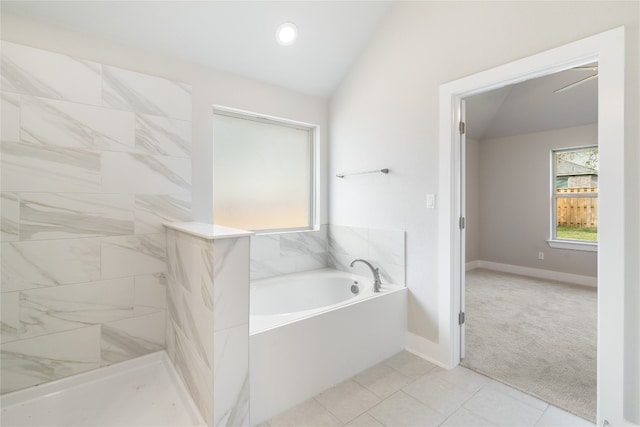 bathroom featuring tile patterned flooring, ceiling fan, vaulted ceiling, and a tub to relax in