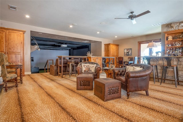 living room with indoor bar, ceiling fan, and light colored carpet