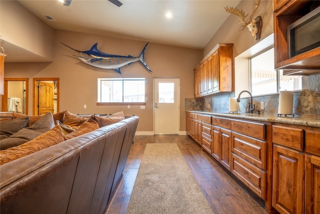 kitchen featuring ceiling fan, sink, tasteful backsplash, and dark wood-type flooring