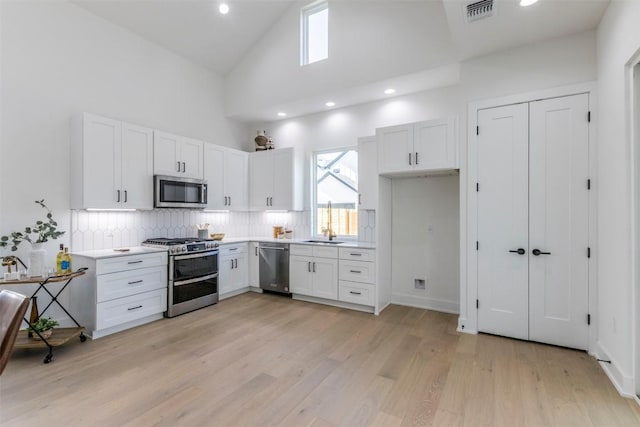 kitchen featuring stainless steel appliances, light countertops, visible vents, light wood-style flooring, and white cabinetry