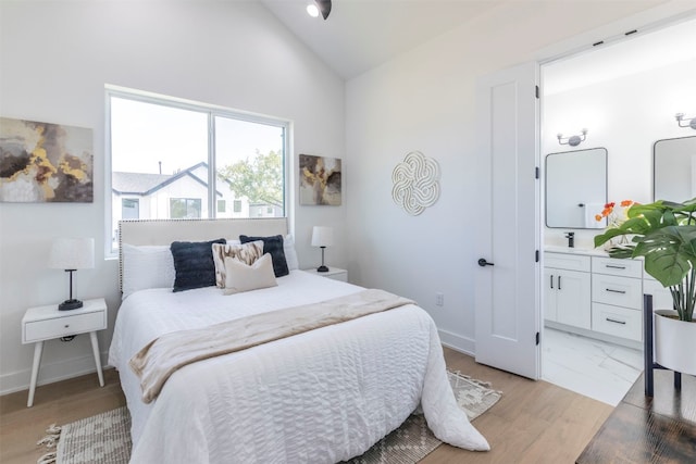 bedroom with high vaulted ceiling, connected bathroom, and light hardwood / wood-style floors