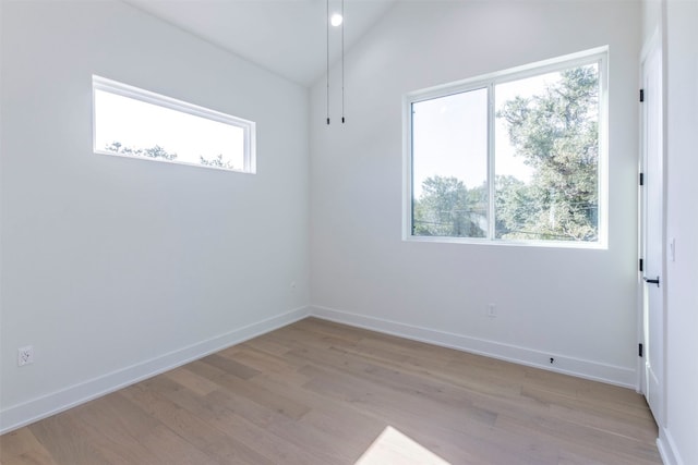 spare room featuring light hardwood / wood-style floors and vaulted ceiling