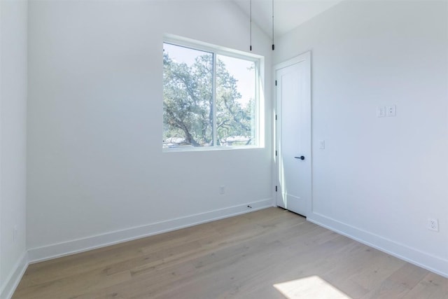 unfurnished room featuring vaulted ceiling, baseboards, and light wood-style floors